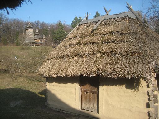 A hut with the Church of Kanora village (1792) in the background, Transcarpathian region