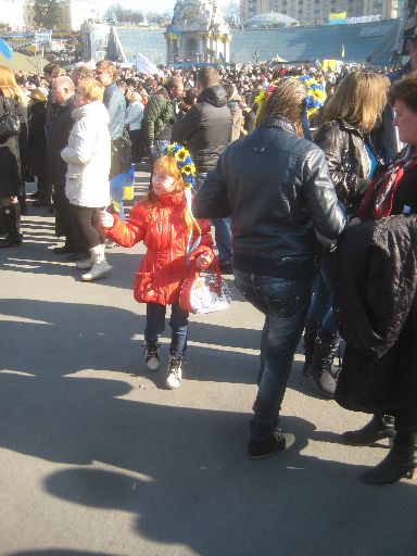 A girl on the Maidan with Euromaidan (and Hello Kitty) paraphernalia, the Independence Monument behind her